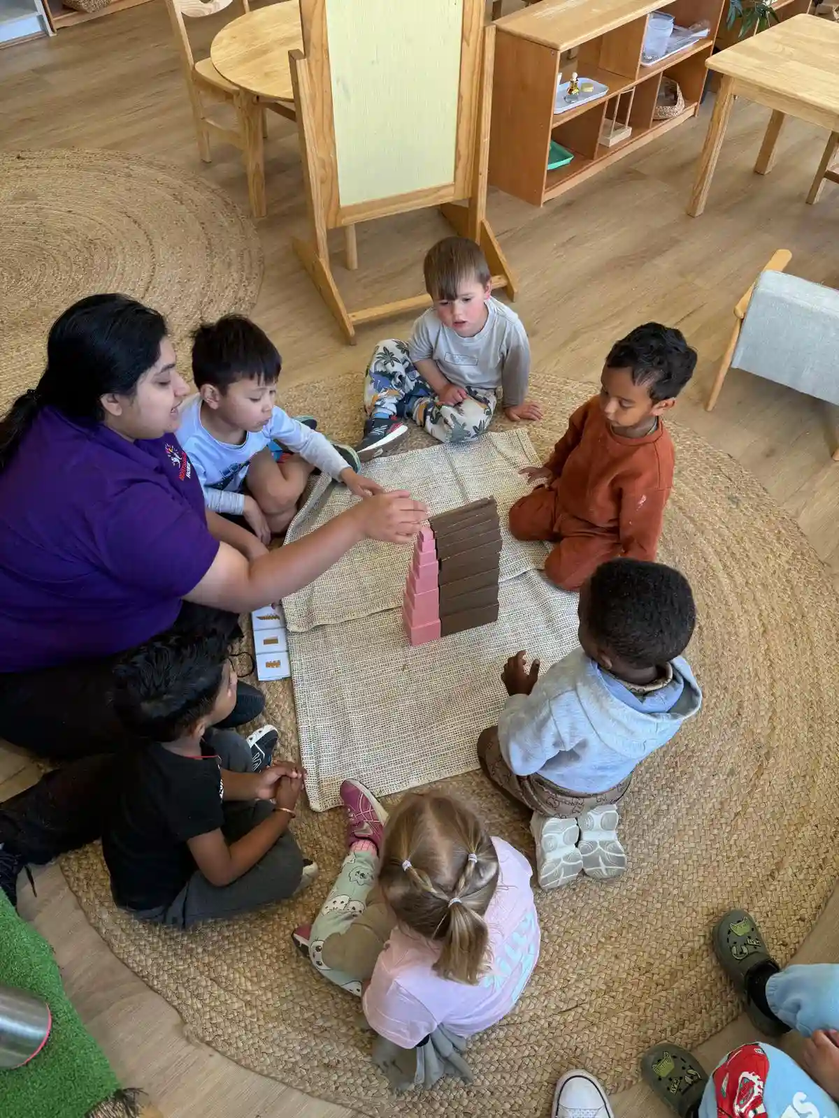 Kindergarten-aged children working with Montessori letter materials on a classroom mat