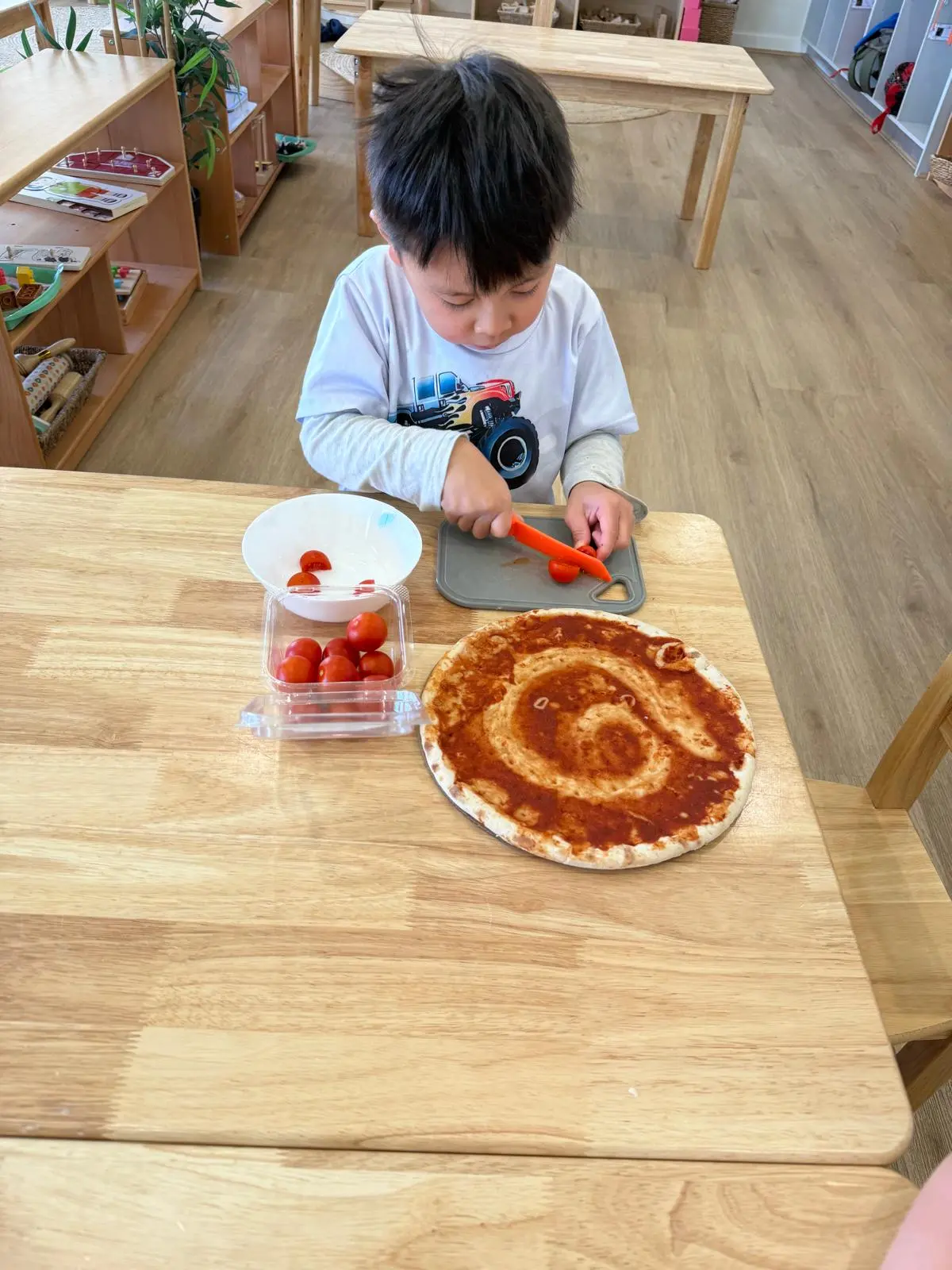 An educator supporting a young child one-on-one with a fine motor threading activity in a quiet corner